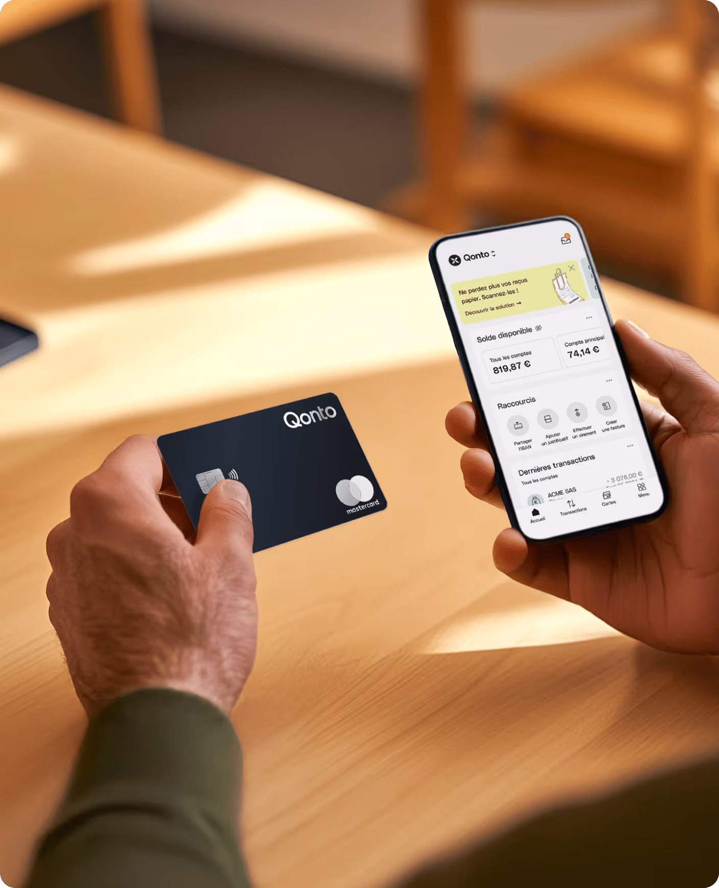 A person holding a smart phone and a Qonto credit card.